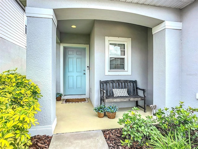 entrance to property featuring stucco siding and a porch