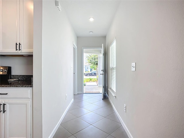 hall featuring baseboards and light tile patterned floors