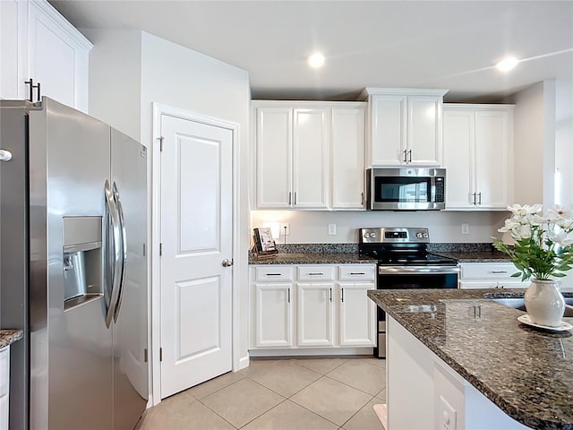 kitchen featuring appliances with stainless steel finishes, light tile patterned floors, white cabinetry, dark stone counters, and recessed lighting