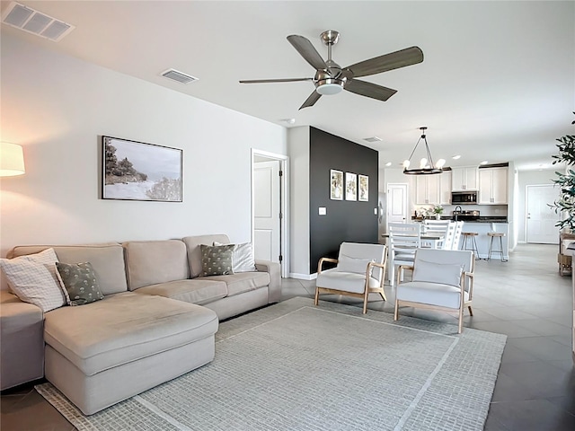 living room with a ceiling fan, a chandelier, and baseboards