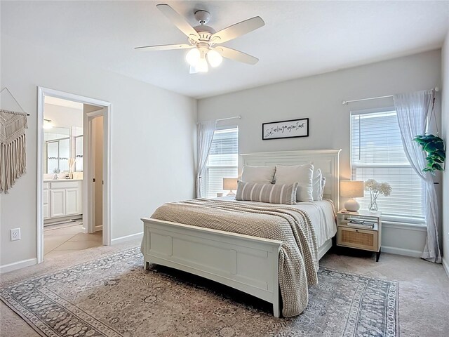 bedroom with light carpet, baseboards, ensuite bath, and ceiling fan