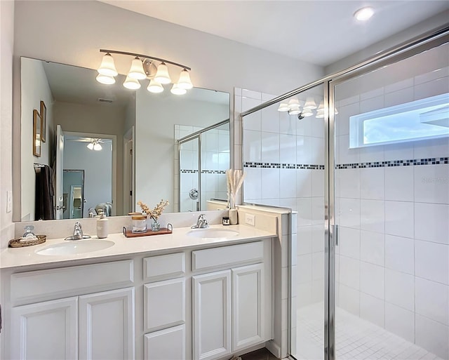 bathroom with a shower stall, double vanity, and ceiling fan