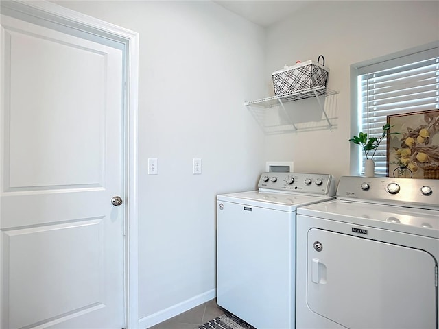 clothes washing area with washer and clothes dryer, dark tile patterned floors, and baseboards