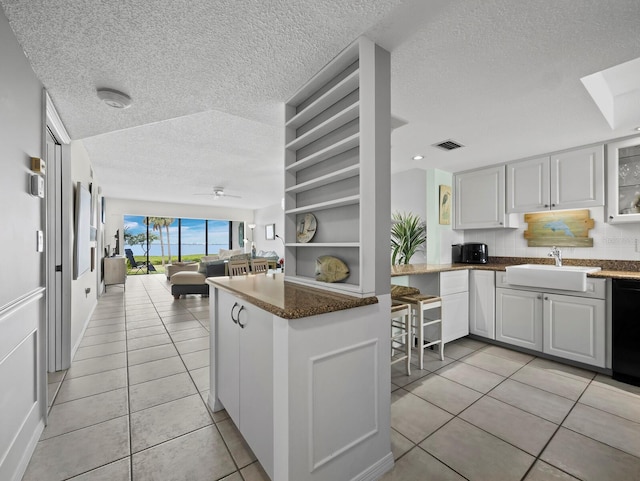 kitchen featuring a sink, light tile patterned floors, a textured ceiling, a ceiling fan, and open floor plan