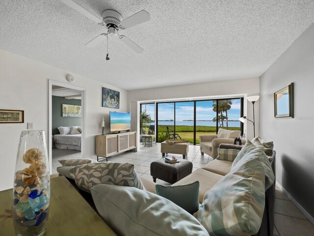 living area featuring tile patterned floors, a textured ceiling, and ceiling fan