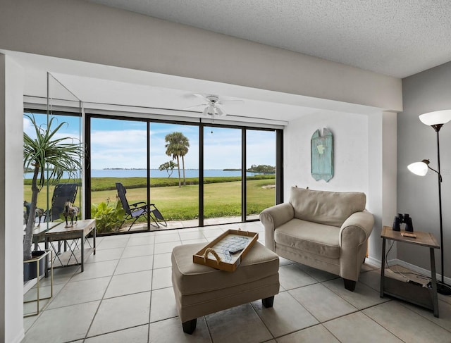 living area with a water view, light tile patterned floors, plenty of natural light, and a textured ceiling