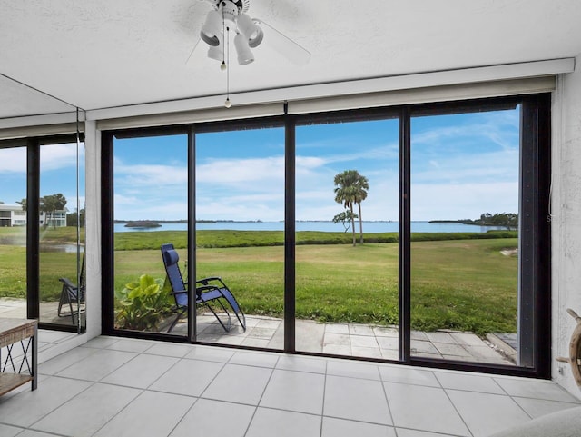 entryway with a water view, a ceiling fan, light tile patterned flooring, and floor to ceiling windows