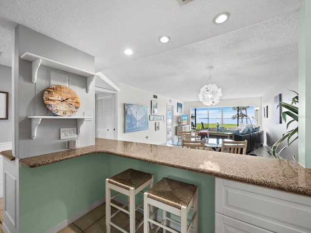 kitchen featuring a textured ceiling, open floor plan, tile patterned floors, a chandelier, and pendant lighting