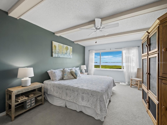 bedroom with beam ceiling, light colored carpet, ceiling fan, and a textured ceiling