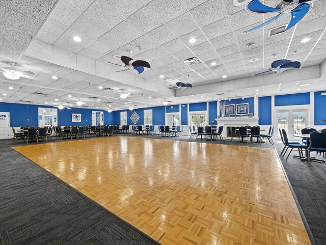 misc room with ceiling fan, a paneled ceiling, and healthy amount of natural light