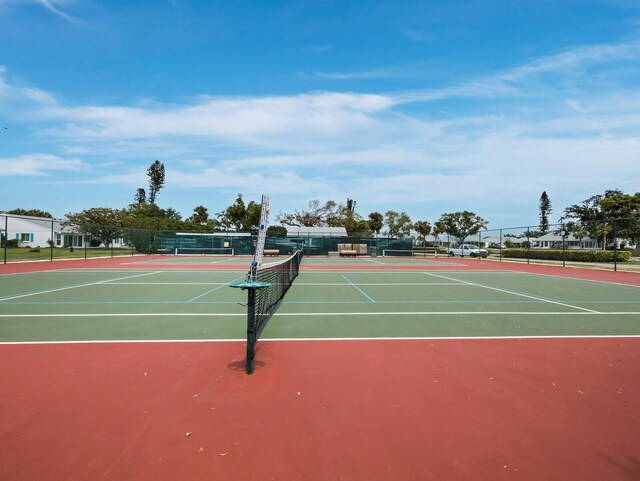 view of tennis court with community basketball court and fence