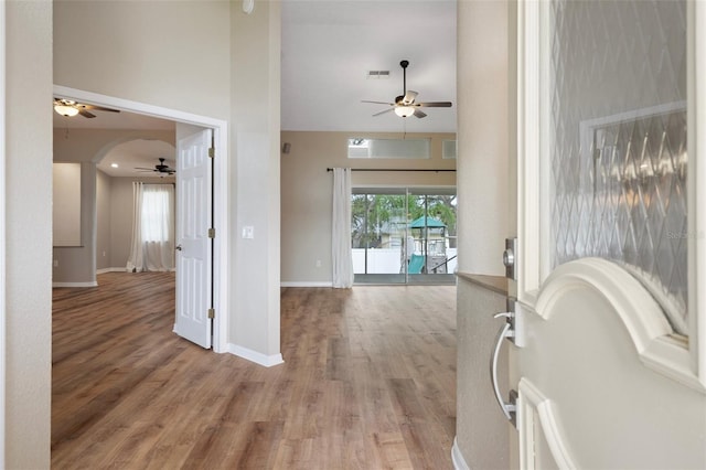 hall featuring light wood-style flooring, high vaulted ceiling, and baseboards