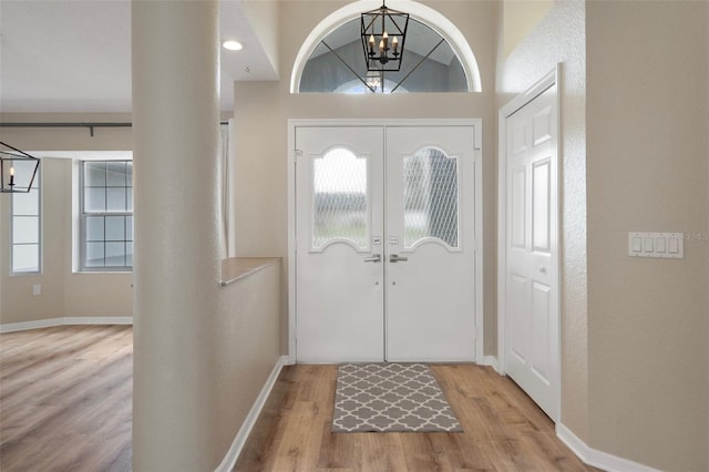 entryway featuring a chandelier, wood finished floors, healthy amount of natural light, and baseboards