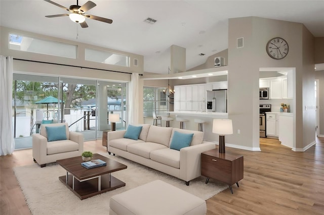 living room featuring light wood-style floors, a ceiling fan, high vaulted ceiling, a chandelier, and baseboards