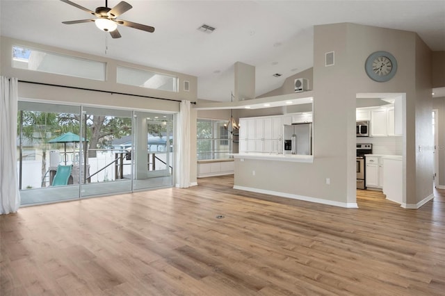 unfurnished living room with ceiling fan, light wood-style floors, high vaulted ceiling, baseboards, and a chandelier