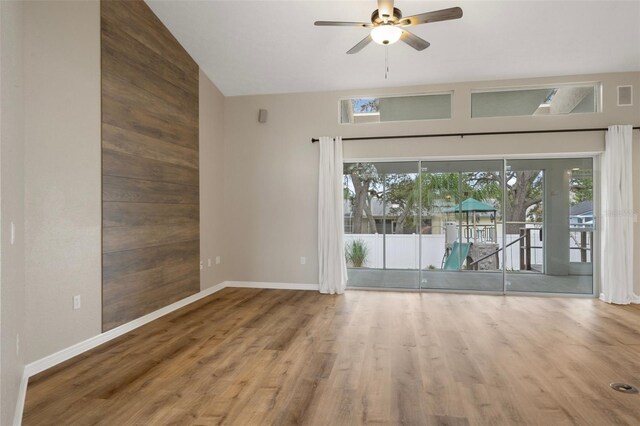 unfurnished room with a ceiling fan, baseboards, wood finished floors, and high vaulted ceiling