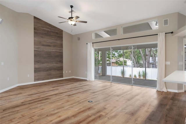 unfurnished living room featuring high vaulted ceiling, ceiling fan, wood finished floors, and baseboards
