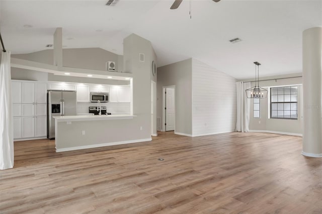 unfurnished living room featuring ceiling fan, a chandelier, light wood-style flooring, high vaulted ceiling, and baseboards