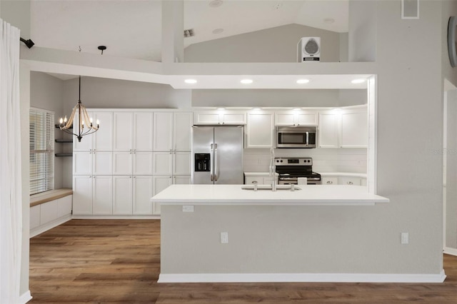 kitchen featuring stainless steel appliances, white cabinetry, vaulted ceiling, wood finished floors, and a sink