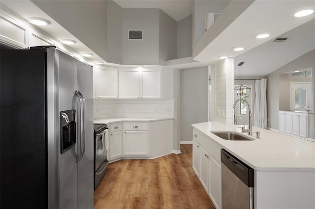 kitchen featuring appliances with stainless steel finishes, a sink, white cabinets, light wood-style flooring, and light countertops