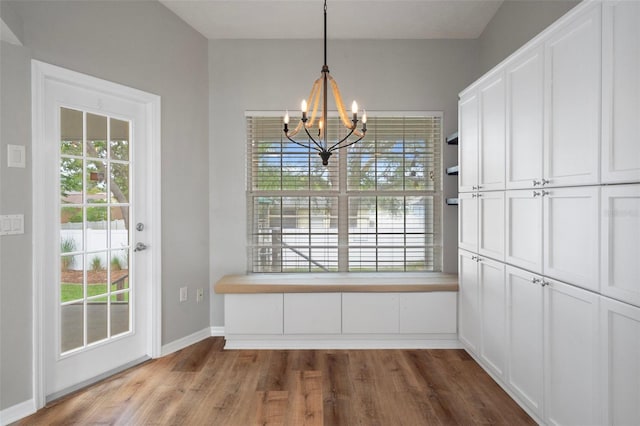 unfurnished dining area featuring a chandelier, wood finished floors, and plenty of natural light