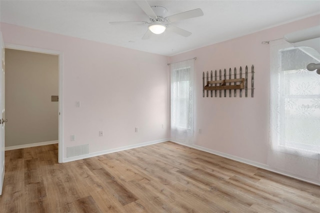 unfurnished room with wood finished floors, a ceiling fan, and baseboards