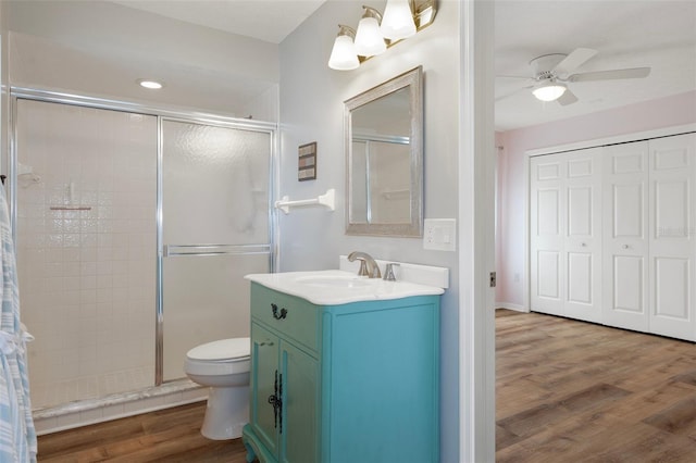 full bathroom with a shower stall, a ceiling fan, wood finished floors, vanity, and toilet