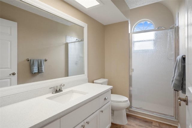 full bath with a stall shower, toilet, wood finished floors, and vanity