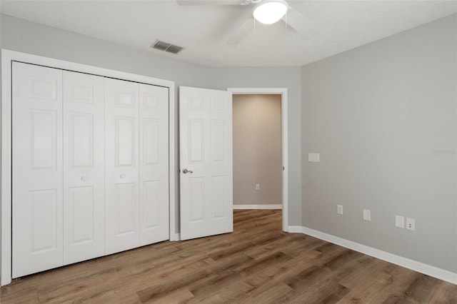 unfurnished bedroom with wood finished floors, baseboards, a closet, and a ceiling fan