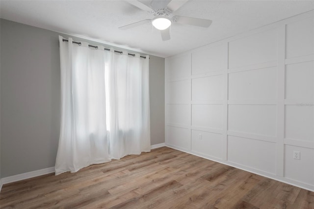 spare room with ceiling fan, wood finished floors, and baseboards