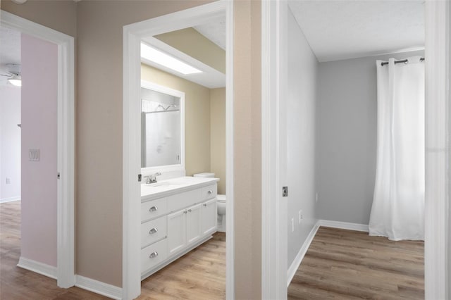 hallway with light wood-type flooring, a sink, and baseboards