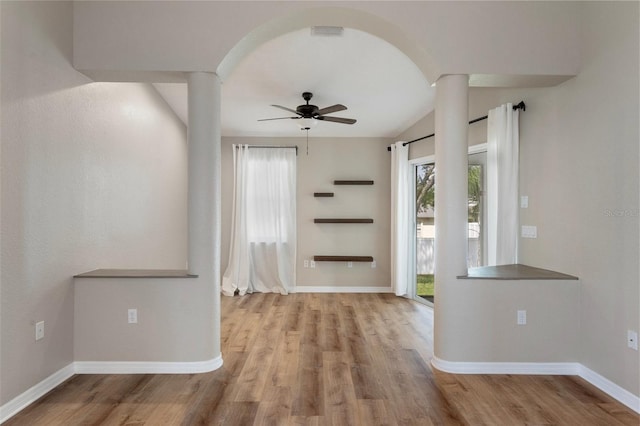 foyer featuring ornate columns, ceiling fan, wood finished floors, baseboards, and arched walkways