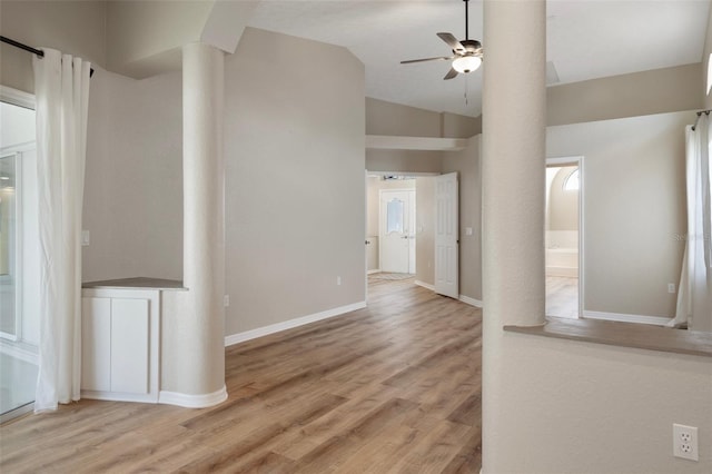 hallway featuring wood finished floors, vaulted ceiling, and baseboards