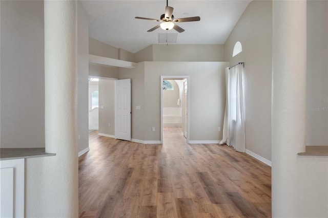 spare room featuring ceiling fan, light wood-style flooring, lofted ceiling, and baseboards