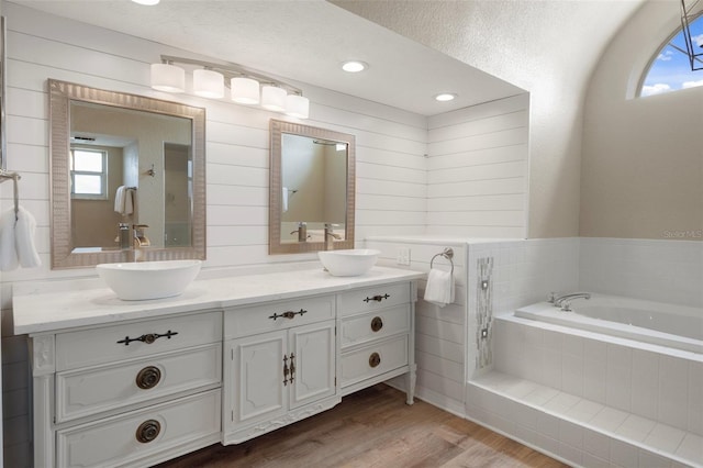 full bathroom with wood finished floors, double vanity, and a garden tub