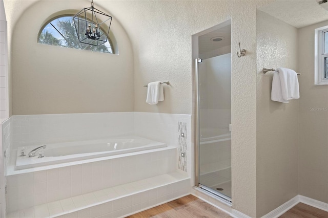 full bathroom with wood finished floors, a shower stall, a bath, and a textured wall