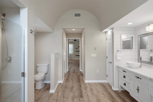 full bathroom with toilet, a shower stall, wood finished floors, vanity, and baseboards
