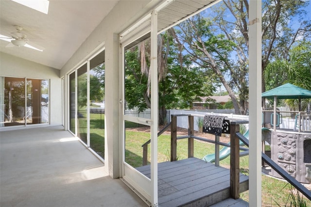 unfurnished sunroom with vaulted ceiling, a ceiling fan, a skylight, and plenty of natural light