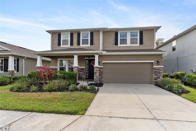 view of front of property featuring stone siding, a garage, a porch, concrete driveway, and a front yard