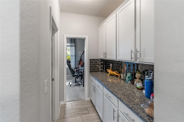 bar area featuring decorative backsplash and a textured ceiling