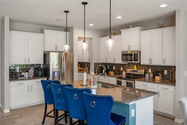 kitchen featuring appliances with stainless steel finishes, a sink, tasteful backsplash, a kitchen breakfast bar, and a kitchen island with sink