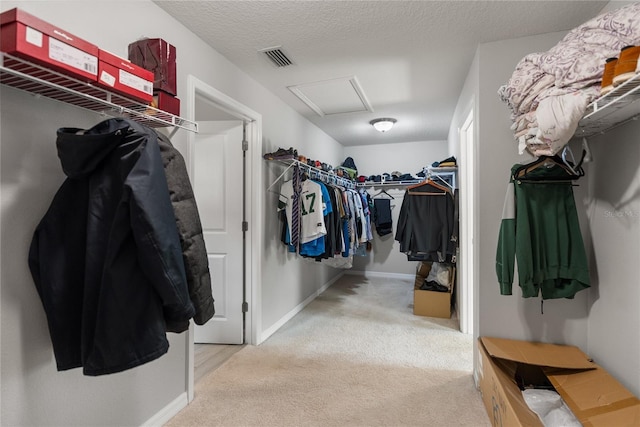 walk in closet with carpet floors and attic access