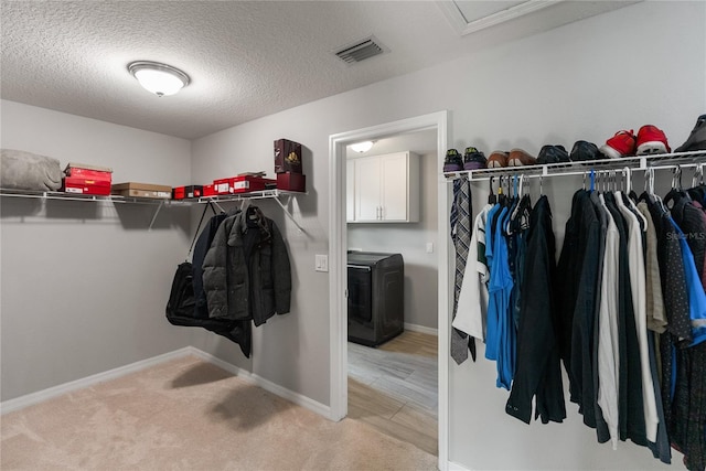 spacious closet featuring washer / clothes dryer, light colored carpet, and attic access