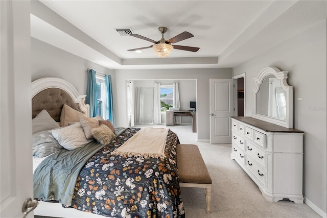 bedroom featuring a tray ceiling, light carpet, baseboards, and ceiling fan