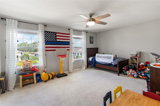 carpeted bedroom with multiple windows, ceiling fan, and baseboards