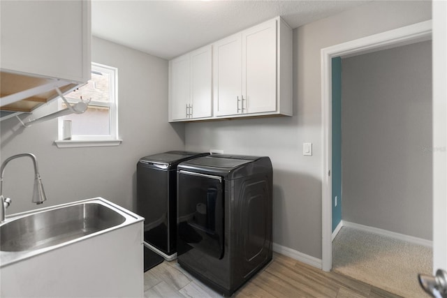 laundry room featuring washer and dryer, cabinet space, baseboards, and light wood-style floors