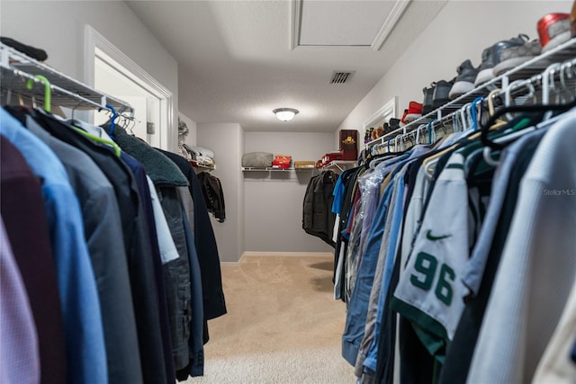 spacious closet with attic access and light carpet