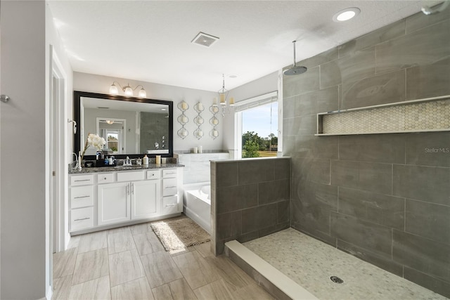 bathroom with a walk in shower, a bath, vanity, and a chandelier