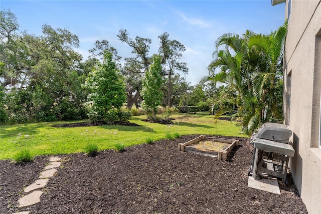 view of grassy yard featuring a vegetable garden and view of wooded area