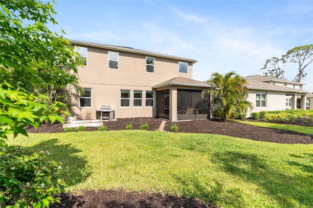 rear view of house with a sunroom, stucco siding, and a yard